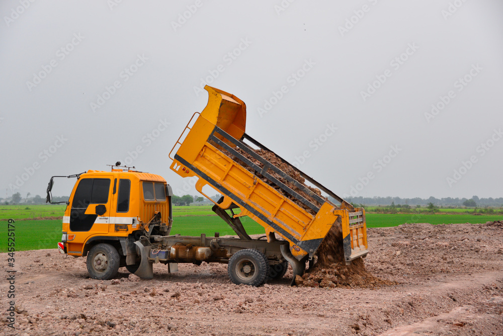 The truck is dumping soil at a construction site