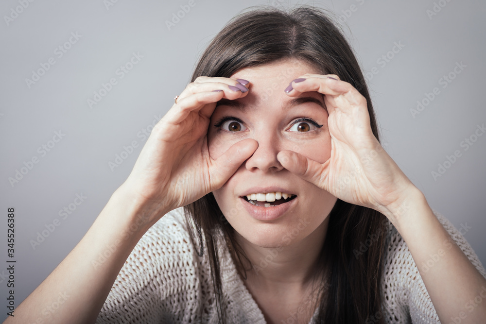 Pretty young woman looking for something with wide open eyes and imaginary binocular. Pretty young woman looking for something with wide open eyes and imaginary binocular.