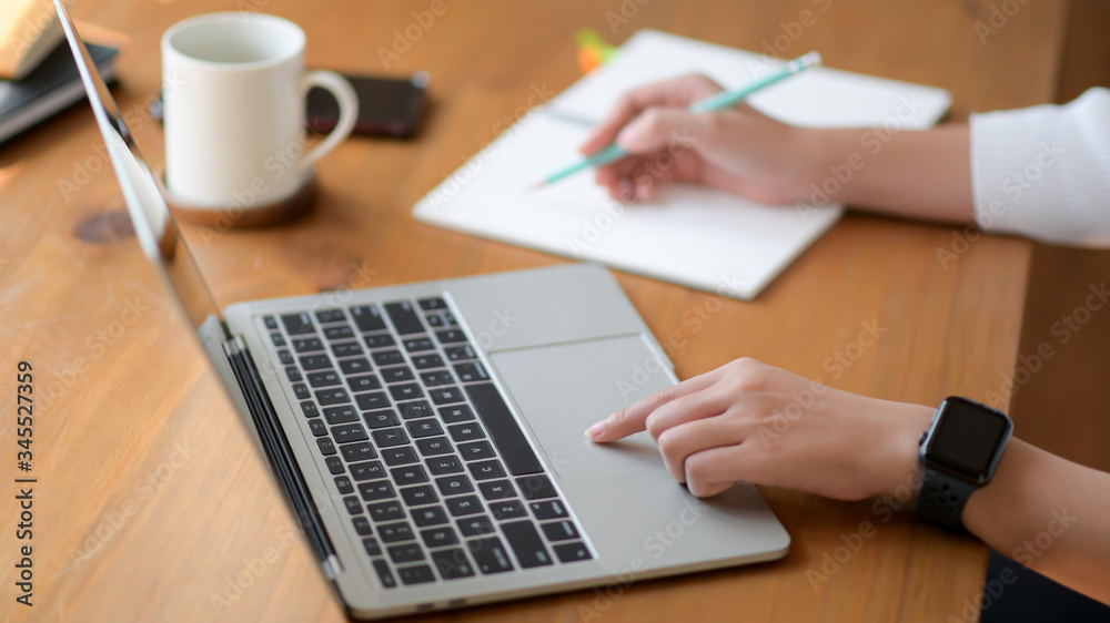 The hand of a young woman using a laptop and writing a report, She works from home. The hand of a young woman using a laptop and writing a report, She works from home.