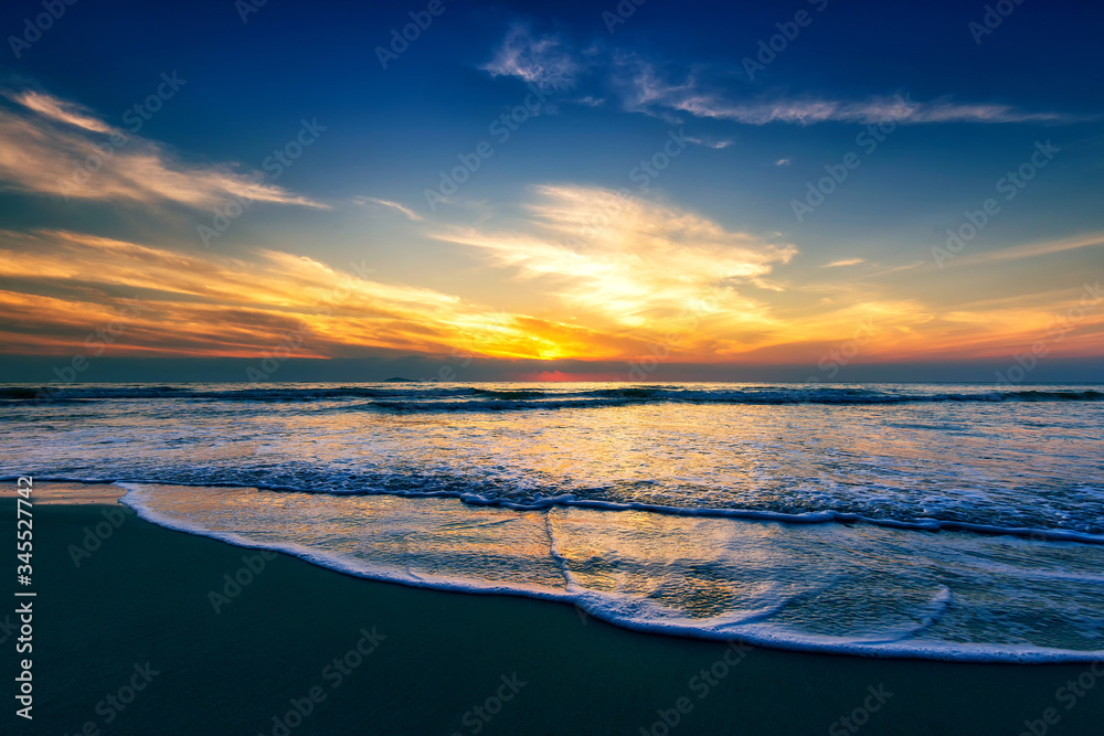 Scenic view of sand beach at the sea in morning sunrise sky.	