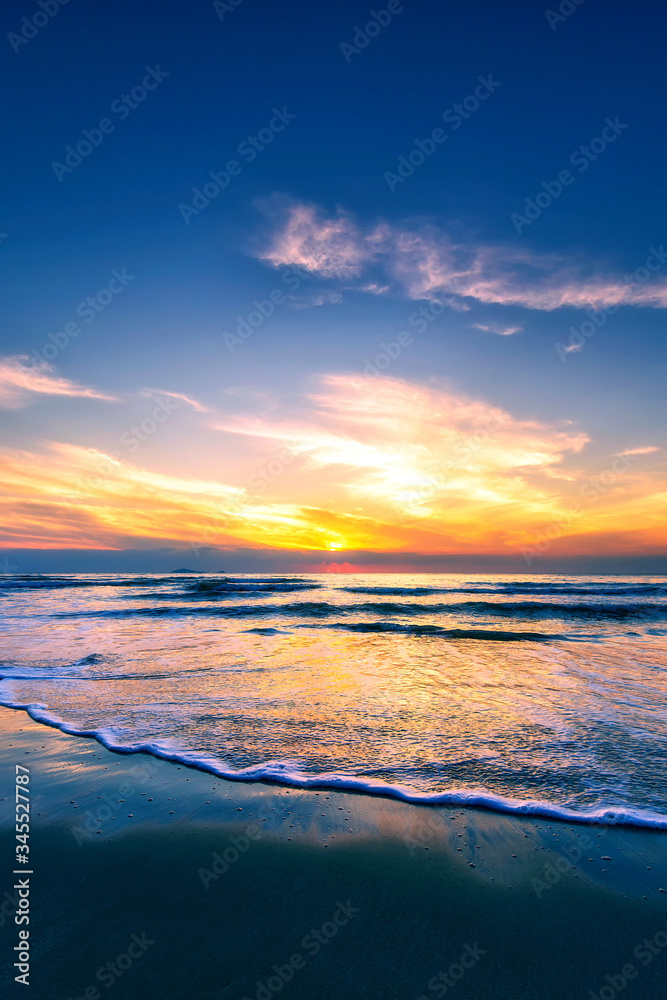 Scenic view of sand beach at the sea in morning sunrise sky.
