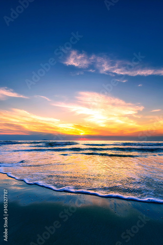 Scenic view of sand beach at the sea in morning sunrise sky.