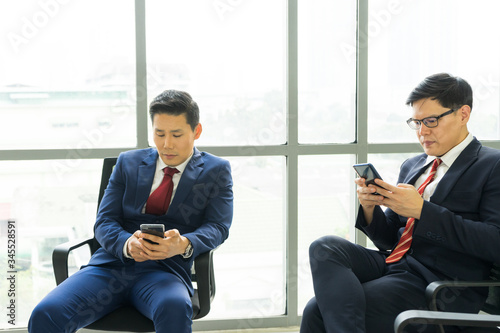 Two business people using smartphone spaced social to prevent the spread of germs and prevention of communicable diseases. Social distancing concept