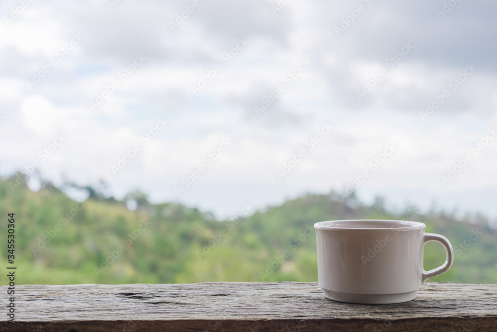 White mug on wooden table over nature background White mug on wooden table over nature background