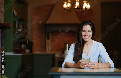 Smiling woman sitting and table and using smartphone
