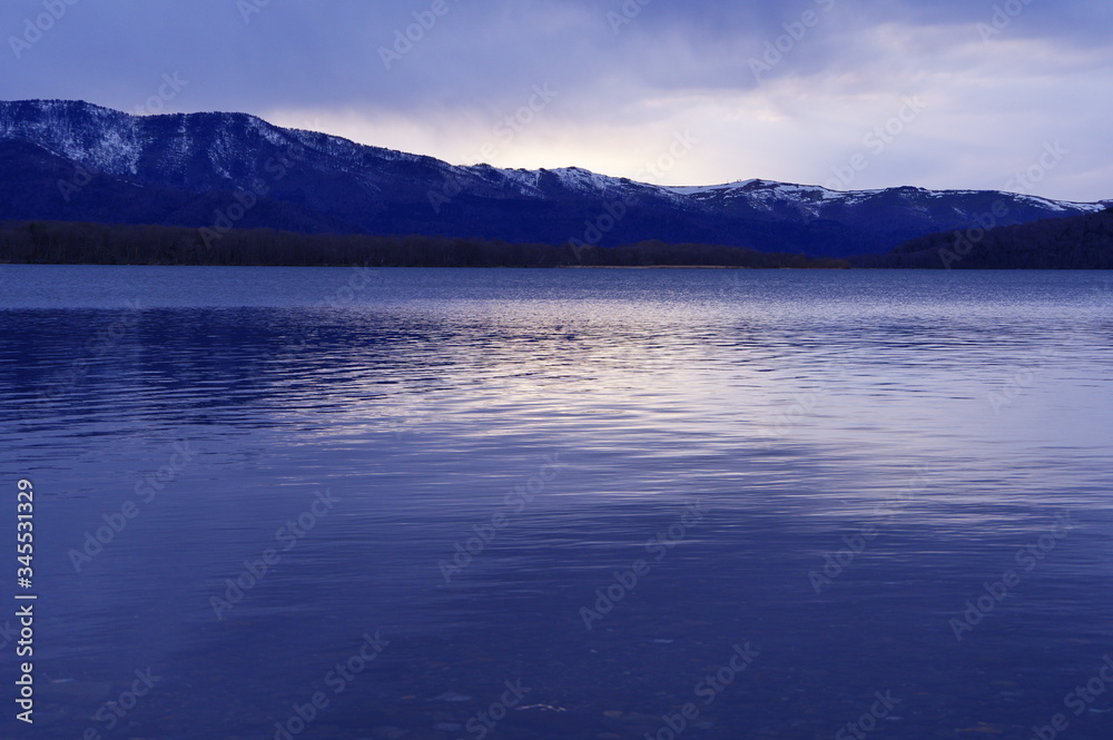 薄明りの中の湖。雲と夕暮れがもたらす風景。屈斜路湖、北海道、日本。