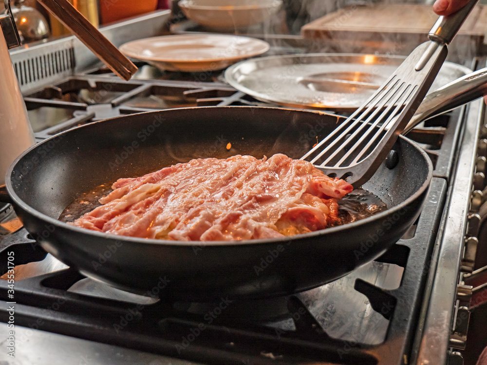 A chef cooks traditional okonomiyaki pancakes in a hot oil in a pan. The Japanese pancake mixture is turned over to see the golden underside. A chef cooks traditional okonomiyaki pancakes in a hot oil in a pan. The Japanese pancake mixture is turned over to see the golden underside.