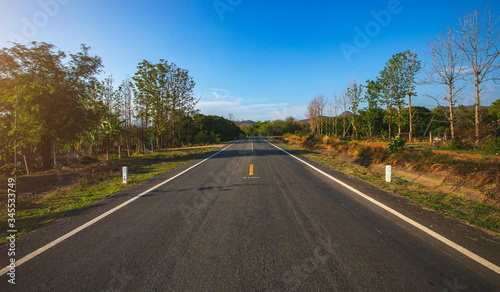 open road. Asphalt road through the green field and clouds on blue sky in summer day. 