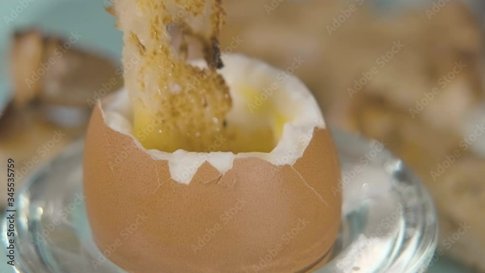 Close-up of dipping toast in a soft boiled egg, also known as the breakfast dish called Eggs and Soldiers.