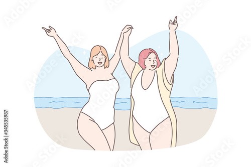 Body positive, vacation, travelling, holiday concept. Young happy obese thick women friends tourists on ocean beach holding hands together. Summer rest or recreation on sea coast and active lifestyle.