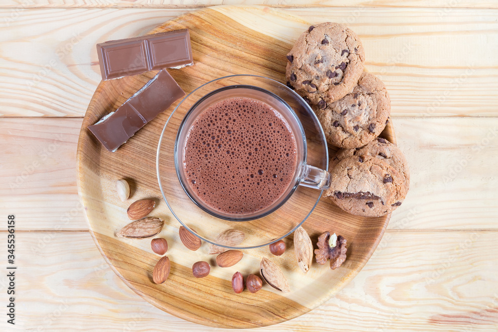 Hot chocolate, nuts and confections on wooden dish, top view