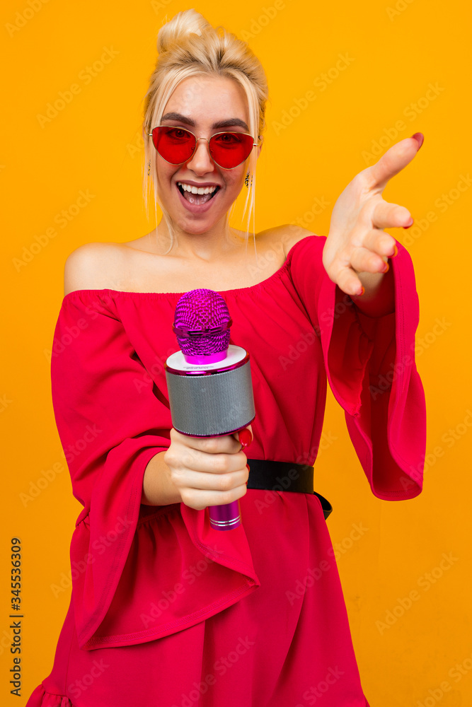 girl in a red elegant dress with bare shoulders with retro glasses holds a microphone and sings girl in a red elegant dress with bare shoulders with retro glasses holds a microphone and sings