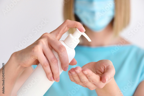 Young woman using antiseptic gel and wearing prevention mask, close up woman hands washing hands with sanitizer to avoid contaminating with Corona virus