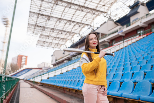 Girl with a bat in an empty stadium.