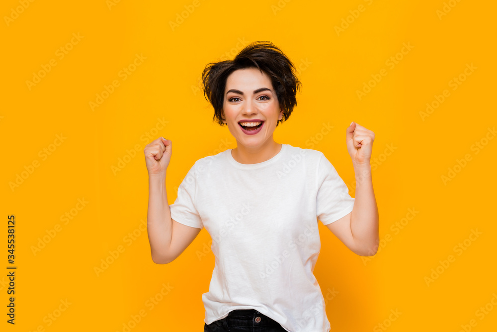 Young happy brunette woman with a short haircut in a white T-shirt on a yellow background. portrait of a young woman with various emotions on a yellow background. space for text Young happy brunette woman with a short haircut in a white T-shirt on a yellow background. portrait of a young woman with various emotions on a yellow background. space for text