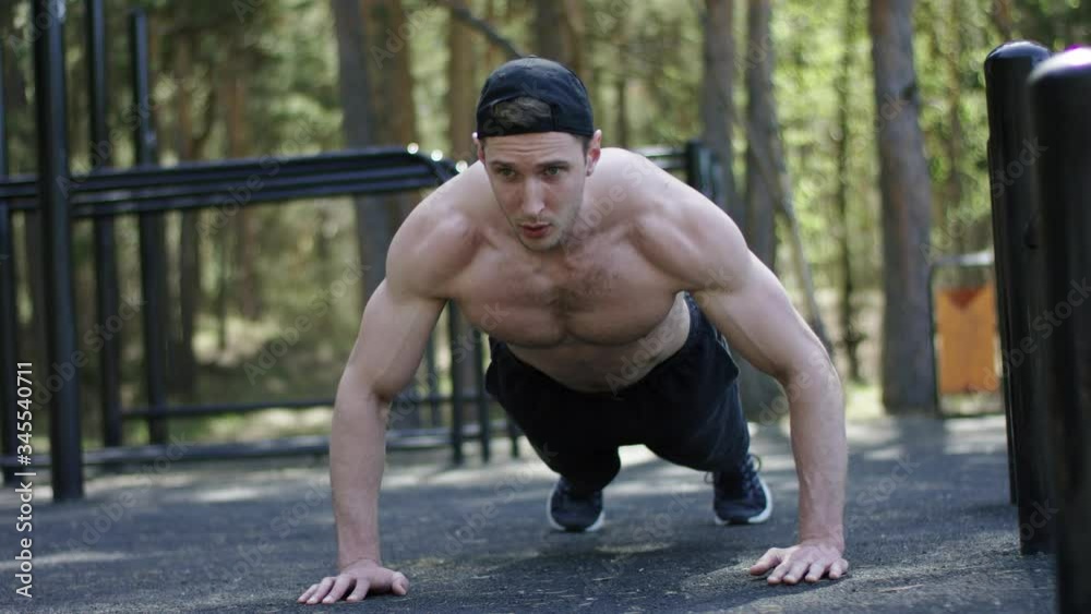 Adult caucasian sportsman is doing push up exercise topless at the gym at the park during his workout