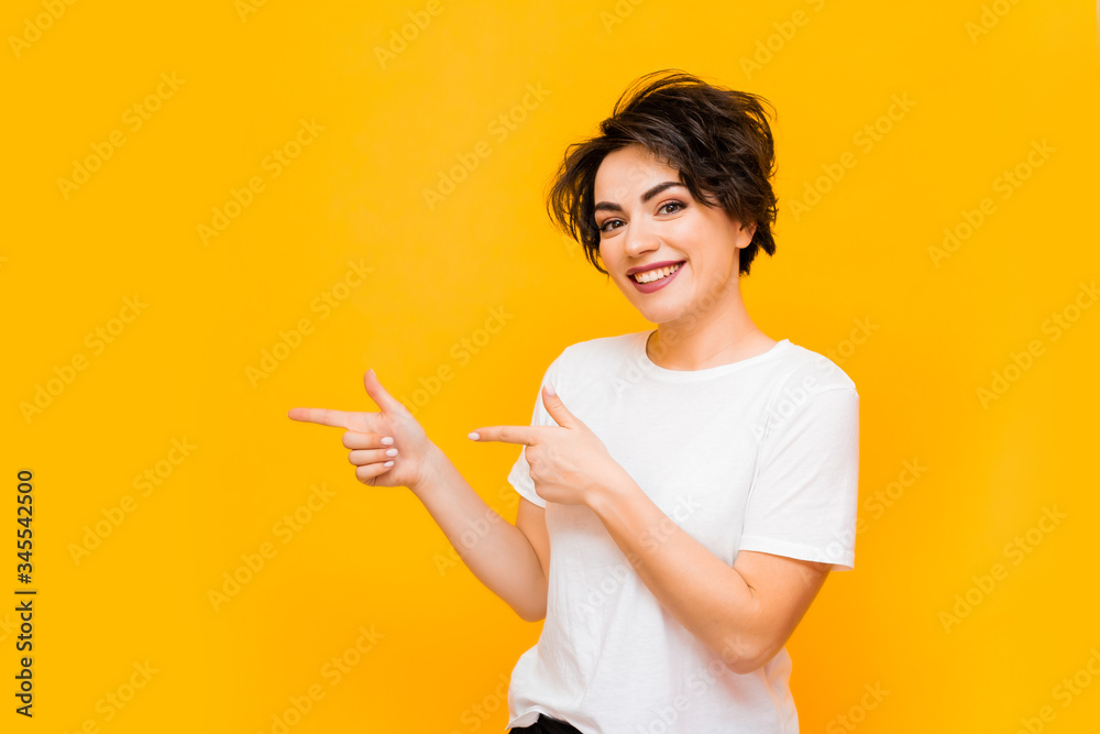 Young happy brunette woman with a short haircut in a white T-shirt on a yellow background. portrait of a young woman with various emotions on a yellow background. space for text Young happy brunette woman with a short haircut in a white T-shirt on a yellow background. portrait of a young woman with various emotions on a yellow background. space for text