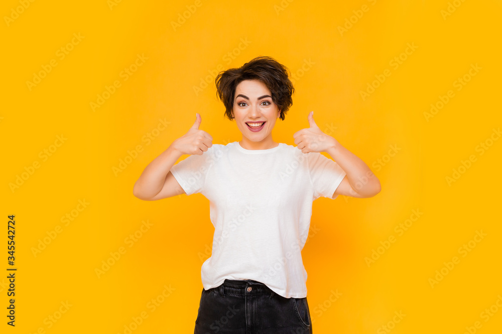 Young happy brunette woman with a short haircut in a white T-shirt on a yellow background. portrait of a young woman with various emotions on a yellow background. space for text Young happy brunette woman with a short haircut in a white T-shirt on a yellow background. portrait of a young woman with various emotions on a yellow background. space for text