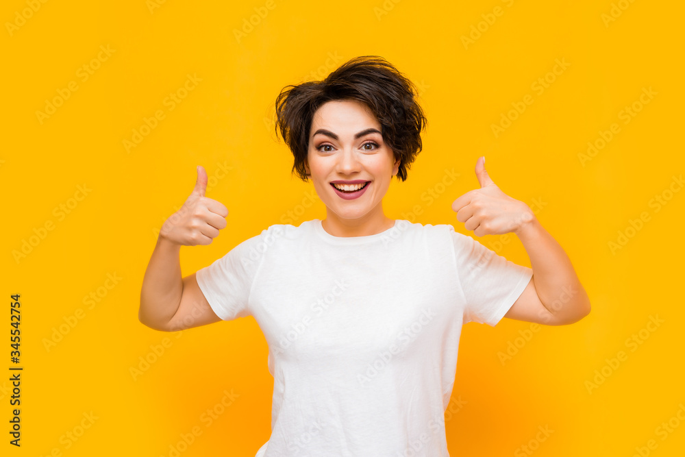 Young happy brunette woman with a short haircut in a white T-shirt on a yellow background. portrait of a young woman with various emotions on a yellow background. space for text Young happy brunette woman with a short haircut in a white T-shirt on a yellow background. portrait of a young woman with various emotions on a yellow background. space for text