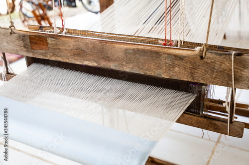 handicraft cotton or silk weaving on wooden loom machine , occupation of villagers at workplace in rural . ancient from asian Thai culture made a clothes for life and for community small business .