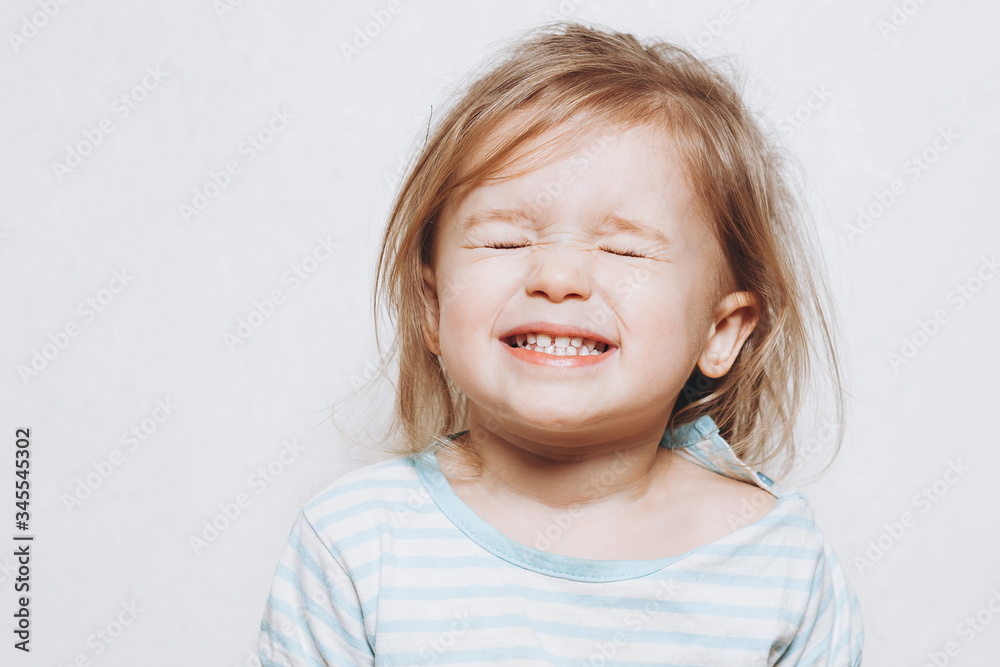 portrait of a little girl of 2 years wearing a red hat and being photographed showing different emotions against a light wall portrait of a little girl of 2 years wearing a red hat and being photographed showing different emotions against a light wall