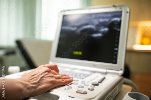 Close up shot of technician operating an ultrasound machine at a clinic. 