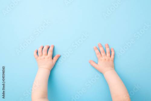 Baby hands on light blue table background. Pastel color. Closeup. Point of view shot. Top view.