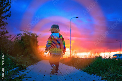 Bilde på lerret Cute toddler child, blond boy in colorful raincoat, holding slinky toy, dragging