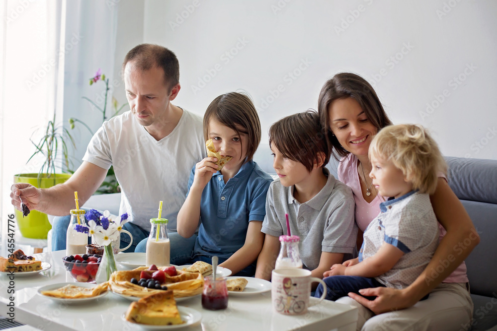 Happy family, having pancakes for breakfast, eating in living room, talking and lauging Happy family, having pancakes for breakfast, eating in living room, talking and lauging
