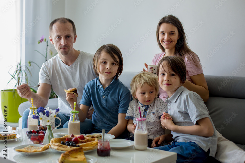Happy family, having pancakes for breakfast, eating in living room, talking and lauging Happy family, having pancakes for breakfast, eating in living room, talking and lauging