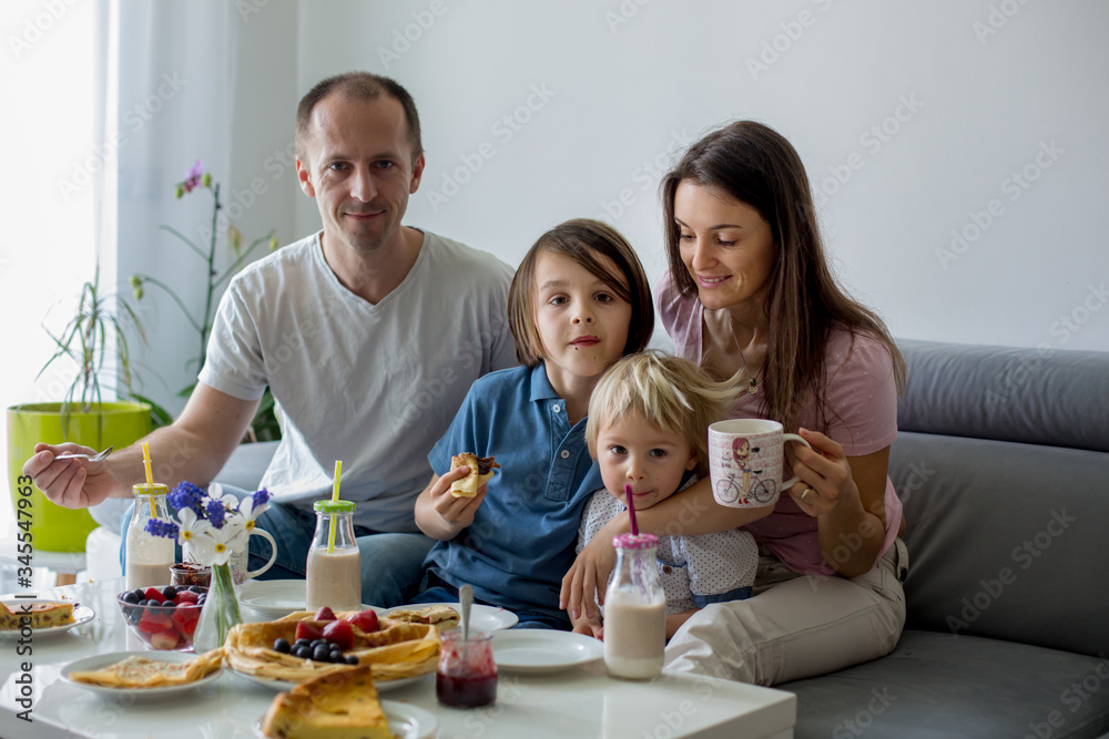 Happy family, having pancakes for breakfast, eating in living room, talking and lauging Happy family, having pancakes for breakfast, eating in living room, talking and lauging