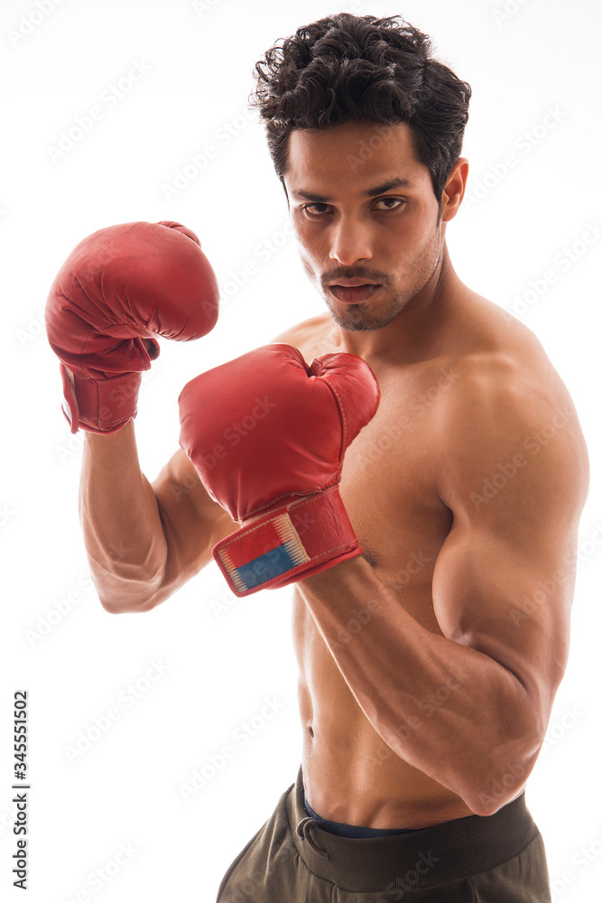 Man wearing boxing gloves and standing in front of a white background.
Man wearing boxing gloves and standing in front of a white background.