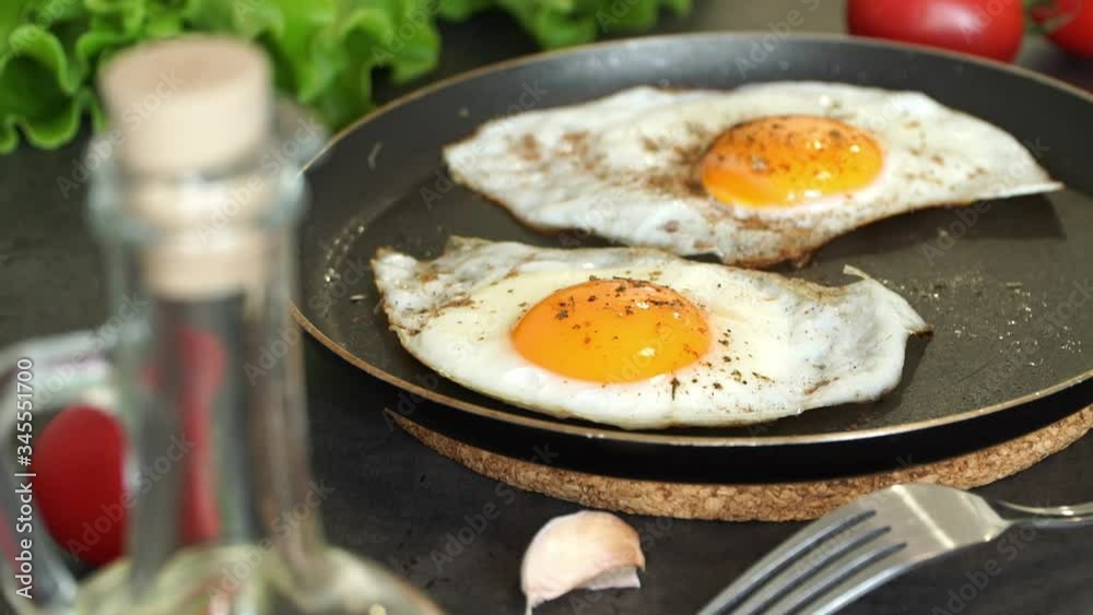 Close up of fried eggs in pan on background of fresh vegetables, olive oil, fresh green salad, tomatoes and garlic. Homemade food. Food background Close up of fried eggs in pan on background of fresh vegetables, olive oil, fresh green salad, tomatoes and garlic. Homemade food. Food background
