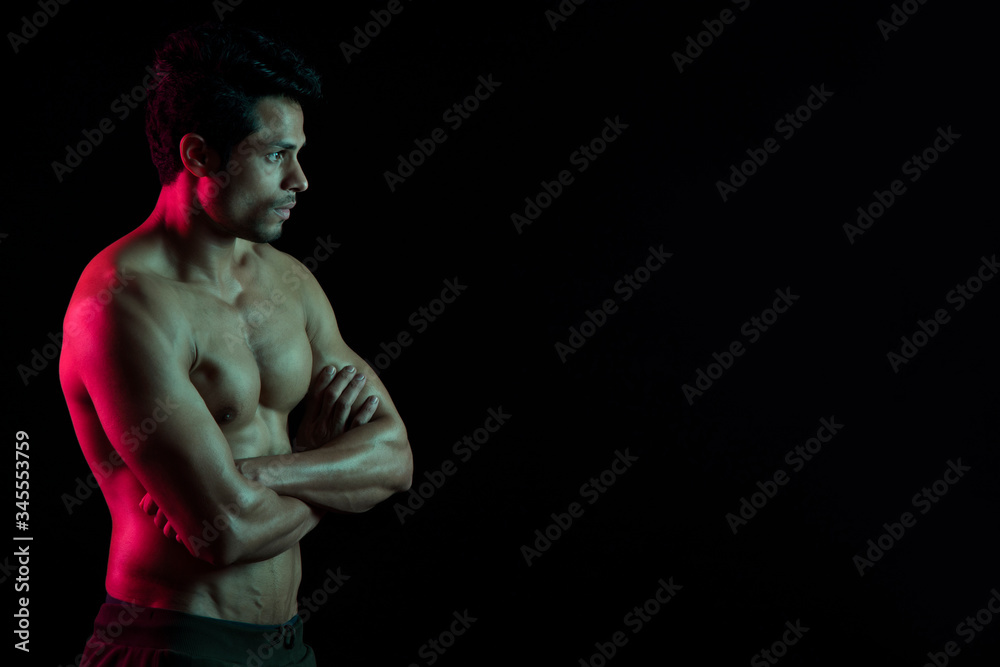 Man flexing his muscles in front of a dark background. 
