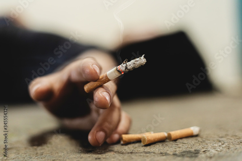 Human hand holding cigarette on floor