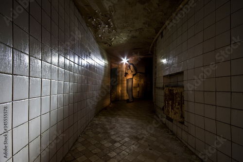 A man with a lantern on his head stands in the corridor in an abandoned building