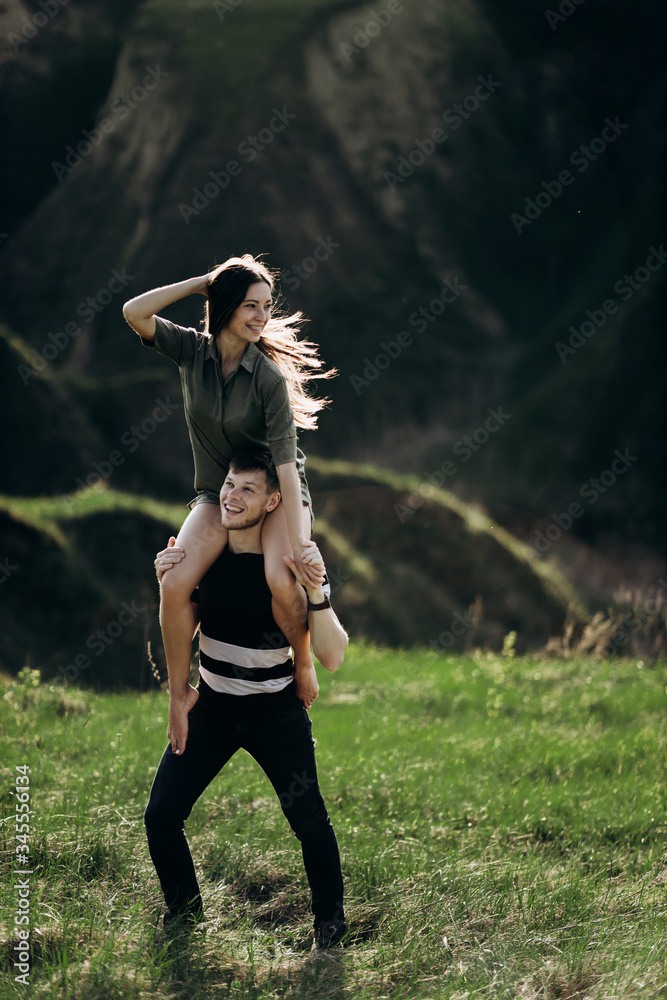 beautiful couple cuddling at sunset on the green hills