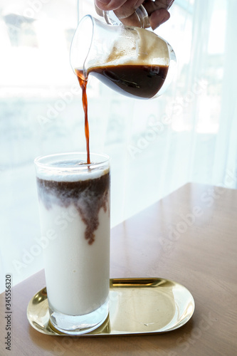 Pouring hot coffee into a glass of cold milk..Coffee is pouring into a glass with milkshake.