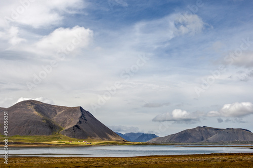 Icelandic landscape with a farm at the foot of a mountain and by the sea