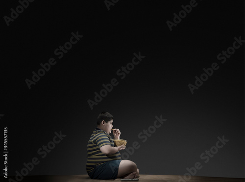 Young boy having chips while watching television.(Obesity) 	