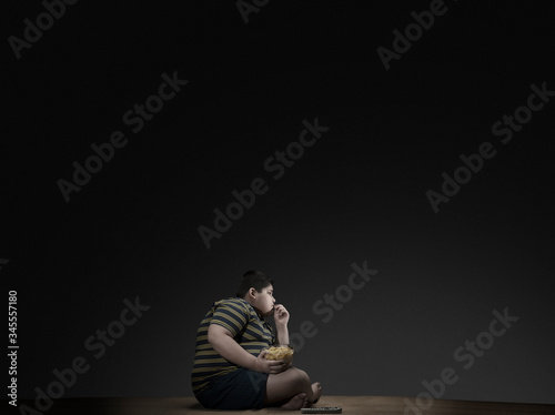 Young boy having chips while watching television.(Obesity) 