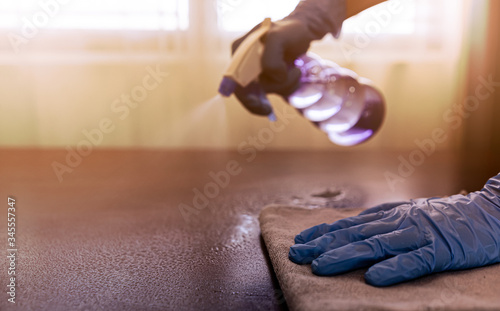 Hands wear blue rubber gloves to prevent germs and use disinfectant sanitizing spray cleaning home or business office to disinfecting coronavirus and prevention against Coronavirus disease 2019  COVID
