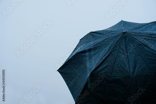 Alone man standing out in rain with an umbrella