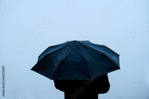 Alone man standing out in rain with an umbrella