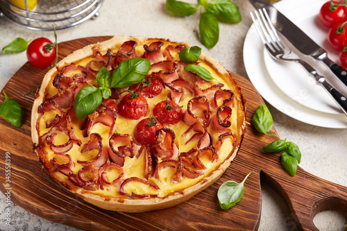 Quiche open tart pie with ham and tomatoes filled with cream, cheese and eggs. Savory taste.