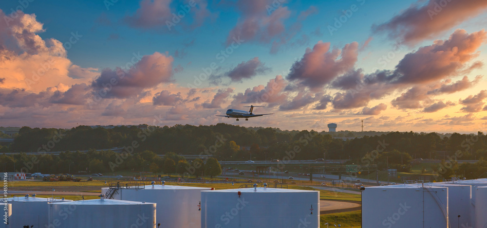 Obraz premium Commercial Jet Plane Descending Over Tanks