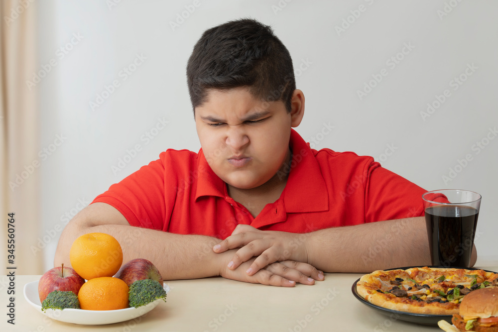 Young boy looking angrily at fruits and vegetables. (Obesity) Young boy looking angrily at fruits and vegetables. (Obesity)