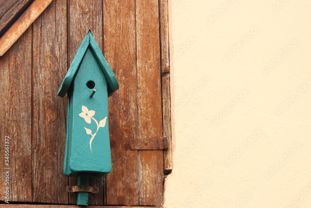birdhouse with a painted flower hanging on a wooden wall