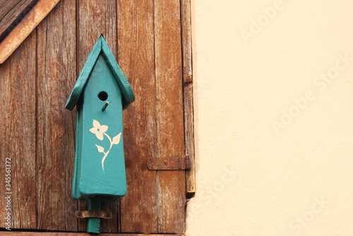 birdhouse with a painted flower hanging on a wooden wall © schapinskaja