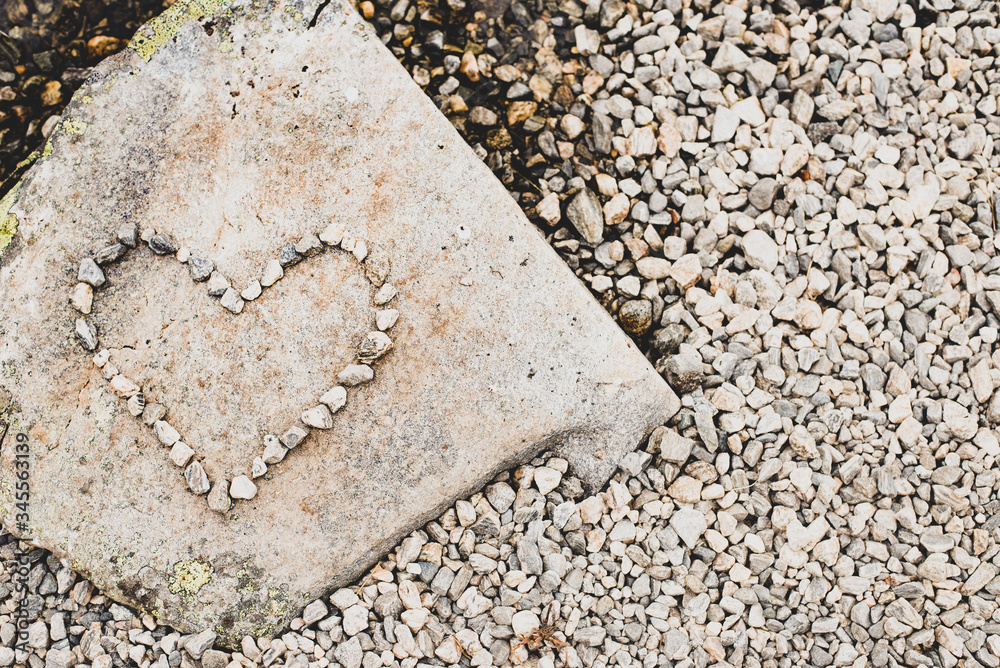 Top view of flat stone with heart shape made of little pebbles located on top of stone. Flatlay of heart shaped stone figure. Stone texture. Place for text. Top view of flat stone with heart shape made of little pebbles located on top of stone. Flatlay of heart shaped stone figure. Stone texture. Place for text.